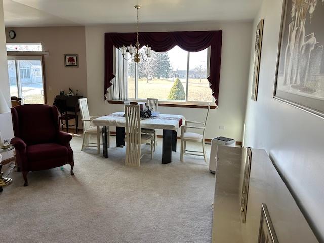 dining room featuring a healthy amount of sunlight, light carpet, and a notable chandelier