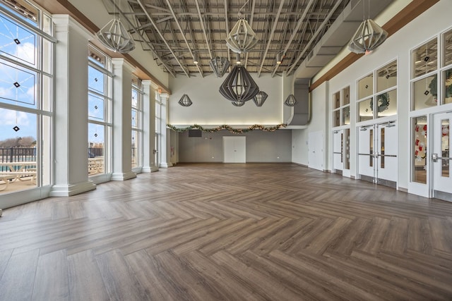 interior space with a towering ceiling, parquet flooring, and a wealth of natural light