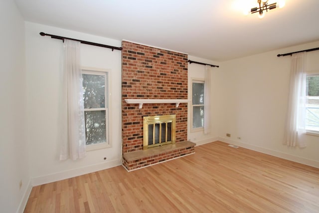 unfurnished living room with a brick fireplace and light hardwood / wood-style flooring