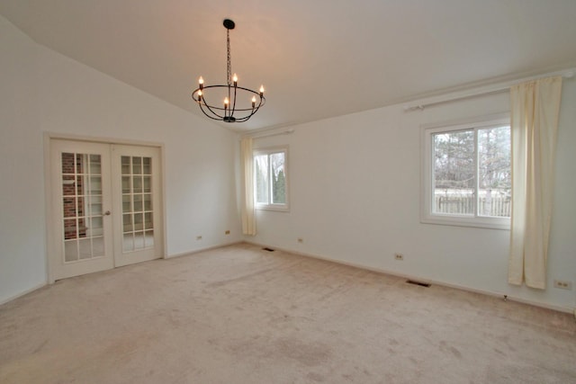 empty room featuring carpet flooring, a notable chandelier, lofted ceiling, and french doors