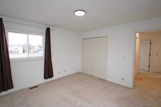 unfurnished bedroom featuring light colored carpet and a closet