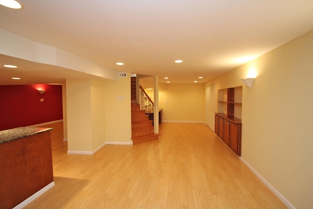 basement with built in shelves and light hardwood / wood-style floors