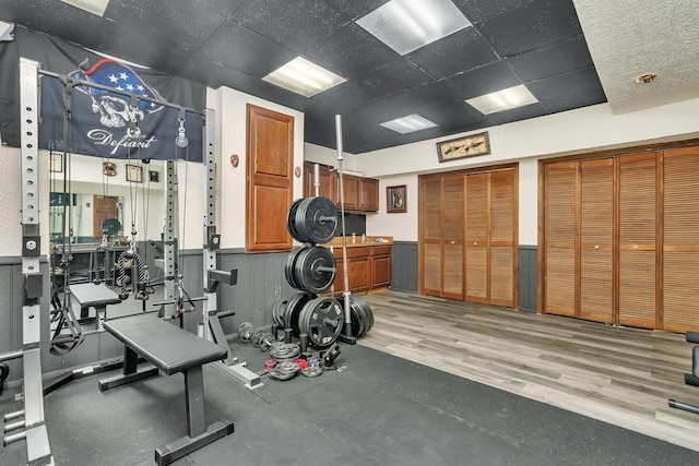 workout room with hardwood / wood-style flooring and a drop ceiling