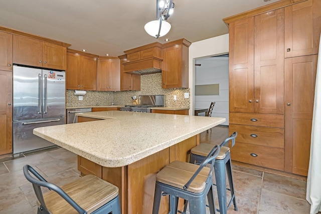 kitchen with a center island, stainless steel appliances, a kitchen breakfast bar, tasteful backsplash, and pendant lighting