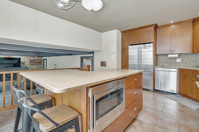 kitchen with built in appliances, a kitchen island, a kitchen bar, and tasteful backsplash