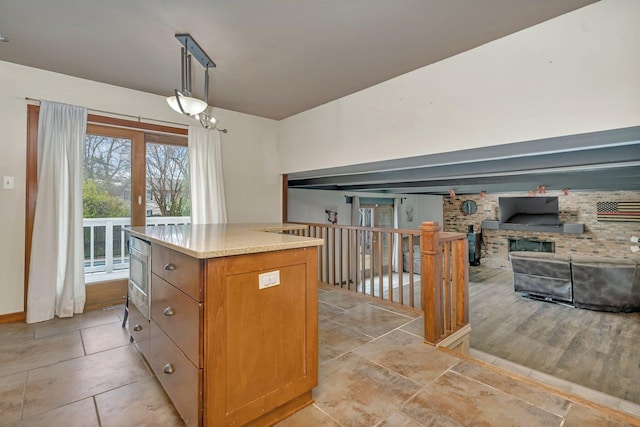 kitchen featuring a fireplace, light stone countertops, a center island, and decorative light fixtures