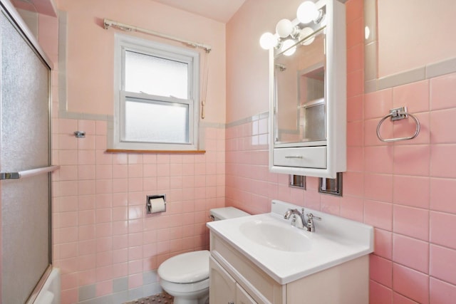 bathroom with vanity, an enclosed shower, tile walls, and toilet