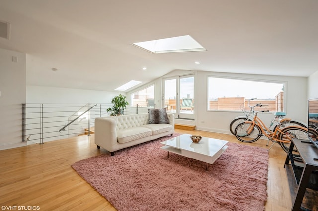 living room featuring plenty of natural light, lofted ceiling with skylight, and light hardwood / wood-style flooring