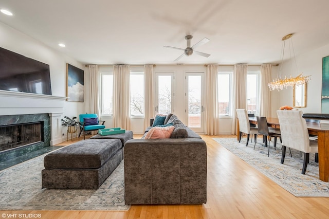 living room featuring ceiling fan, light hardwood / wood-style floors, and a high end fireplace