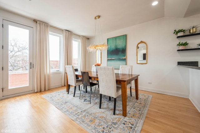 dining area featuring light hardwood / wood-style floors, a notable chandelier, and lofted ceiling