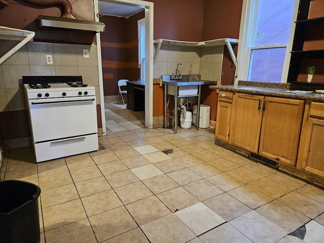 kitchen with decorative backsplash, light tile patterned floors, and white range with gas cooktop