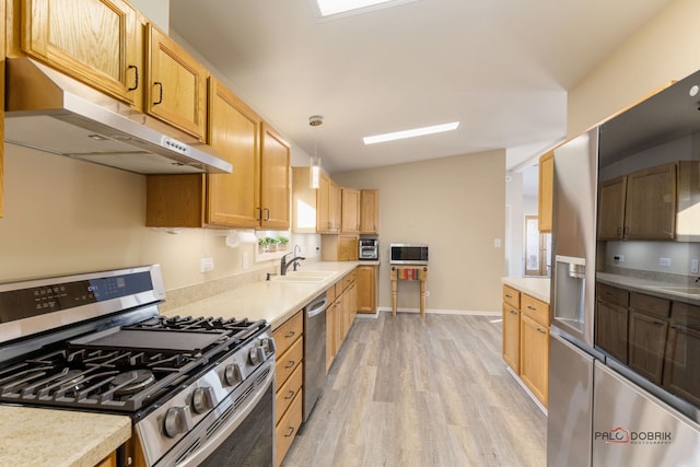 kitchen featuring pendant lighting, sink, light hardwood / wood-style flooring, stainless steel appliances, and vaulted ceiling