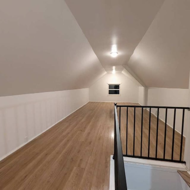 additional living space featuring vaulted ceiling and hardwood / wood-style flooring