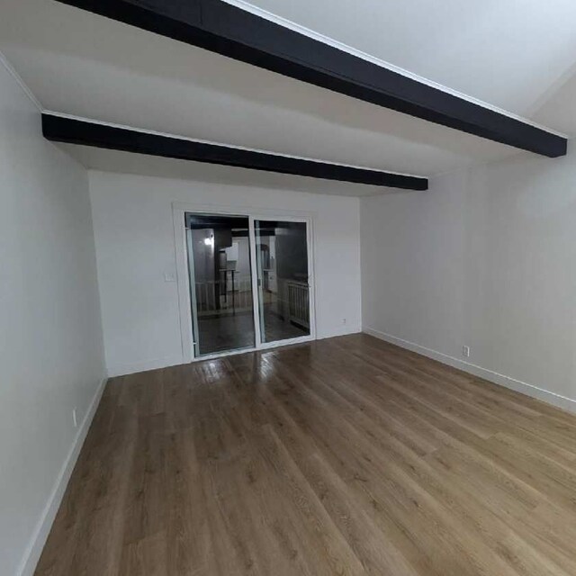 empty room featuring beamed ceiling and hardwood / wood-style floors