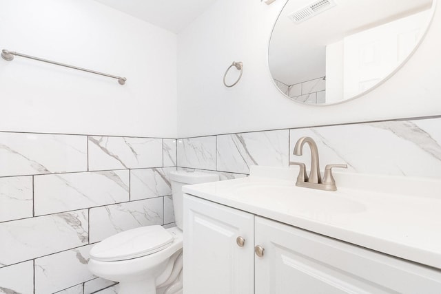 bathroom with vanity, tile walls, and toilet