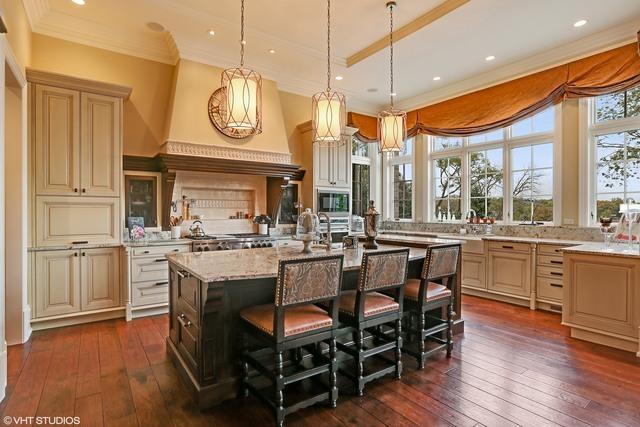 kitchen featuring built in microwave, light stone countertops, dark hardwood / wood-style flooring, an island with sink, and a breakfast bar area