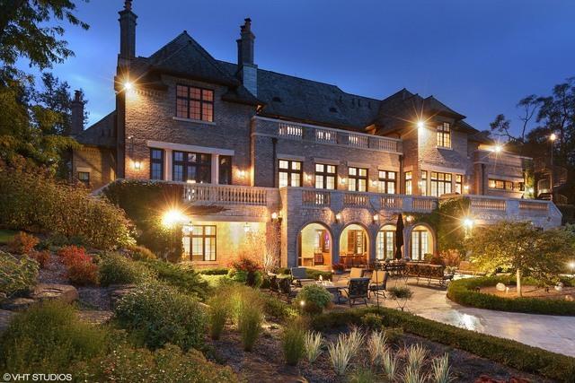 back house at dusk featuring a balcony and a patio