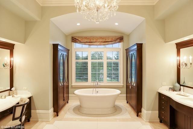 bathroom with tile patterned floors, vanity, an inviting chandelier, and a bathtub