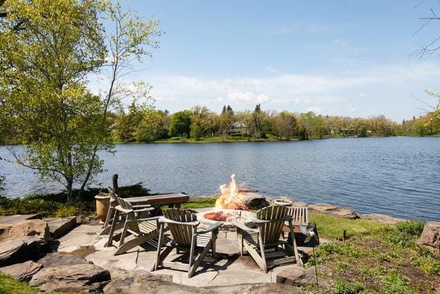 exterior space featuring a water view, an outdoor fire pit, and a patio area