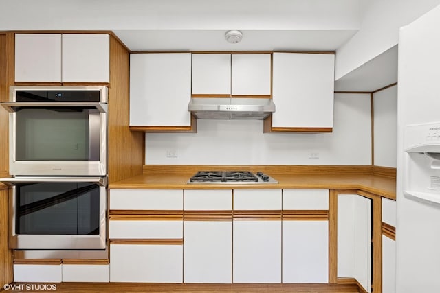 kitchen with stainless steel appliances, light countertops, white cabinetry, and under cabinet range hood