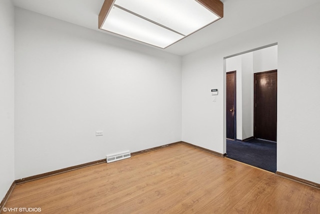 unfurnished room with baseboards, visible vents, and wood finished floors