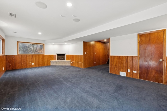 empty room with visible vents, a wainscoted wall, and wooden walls