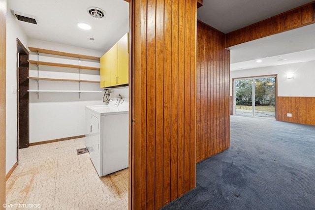 washroom with cabinet space, wooden walls, visible vents, a wainscoted wall, and washing machine and clothes dryer