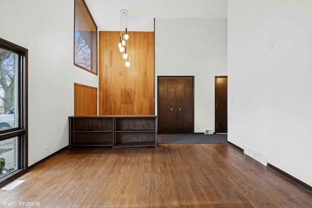 interior space with a towering ceiling, visible vents, and wood finished floors