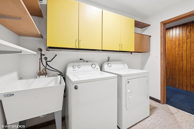 washroom featuring washer and dryer, cabinet space, a sink, and baseboards