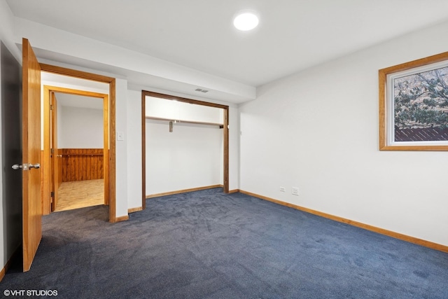 unfurnished bedroom with baseboards, visible vents, dark carpet, and a closet