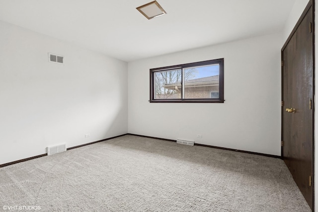 spare room with carpet, visible vents, and baseboards