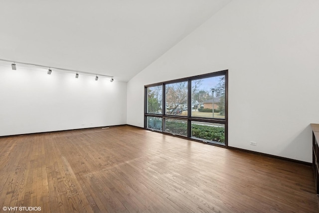 spare room featuring high vaulted ceiling, track lighting, baseboards, and wood finished floors