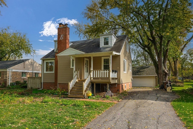 view of front facade with a front lawn, covered porch, an outdoor structure, and a garage