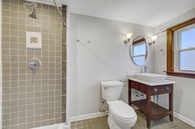 bathroom with toilet, vanity, and tiled shower