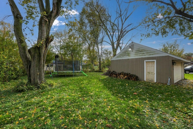 view of yard featuring a garage, an outdoor structure, and a trampoline