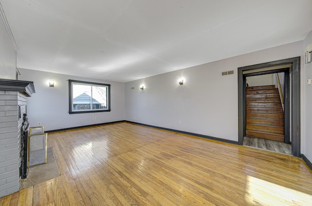 unfurnished living room with light hardwood / wood-style floors and a brick fireplace