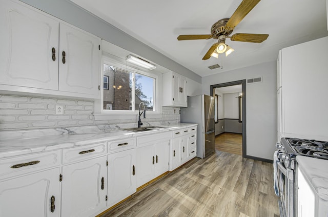 kitchen featuring stainless steel appliances, ceiling fan, sink, light hardwood / wood-style flooring, and white cabinets