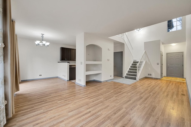 unfurnished living room with built in shelves, light hardwood / wood-style flooring, and a chandelier