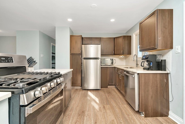 kitchen with light hardwood / wood-style floors, sink, and stainless steel appliances