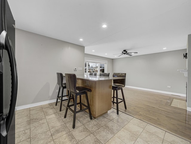 kitchen featuring a breakfast bar, ceiling fan, light wood-type flooring, and kitchen peninsula