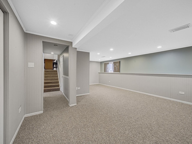 basement featuring carpet, wood walls, and ornamental molding