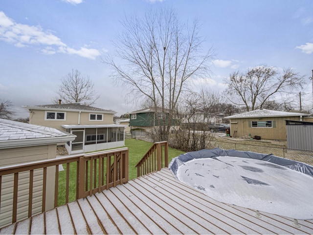 wooden terrace featuring a lawn and a sunroom