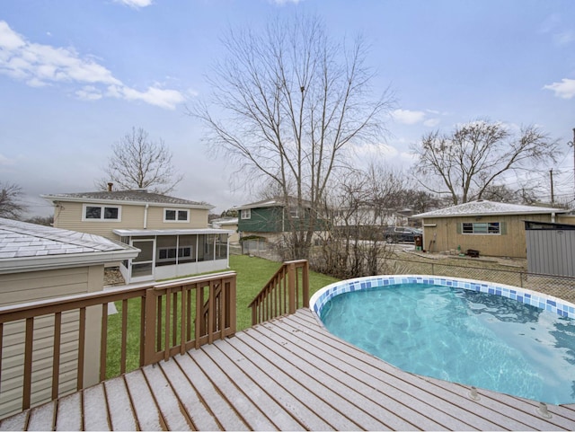 view of pool featuring a sunroom, an outdoor structure, a yard, and a wooden deck