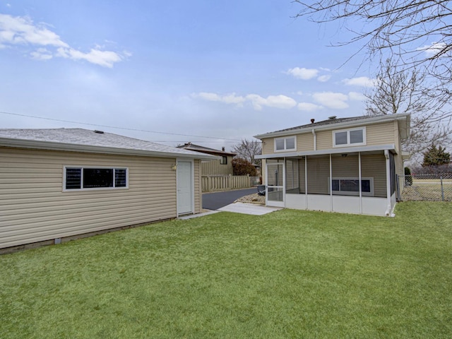 back of house featuring a sunroom and a lawn