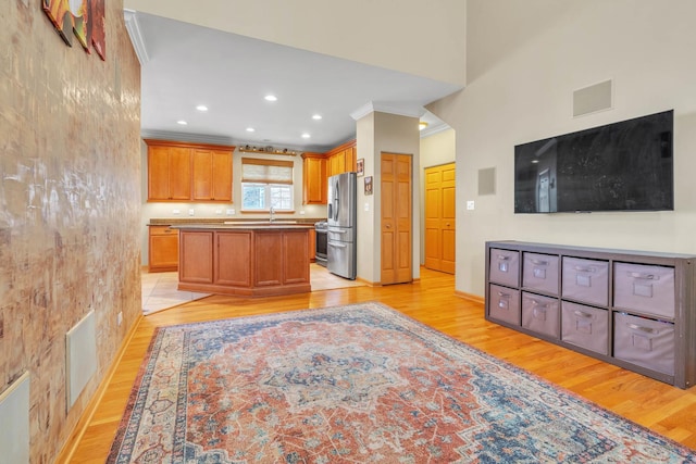 kitchen featuring sink, crown molding, light wood-type flooring, a kitchen island, and stainless steel refrigerator