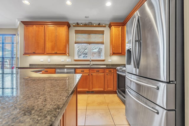 kitchen with appliances with stainless steel finishes, dark stone counters, ornamental molding, and sink