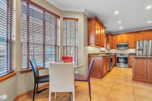 kitchen with ornamental molding, stainless steel appliances, plenty of natural light, and dark stone counters