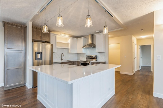 kitchen featuring appliances with stainless steel finishes, wall chimney range hood, a center island, white cabinetry, and hanging light fixtures