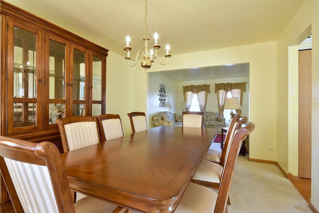 dining area featuring light carpet and a notable chandelier