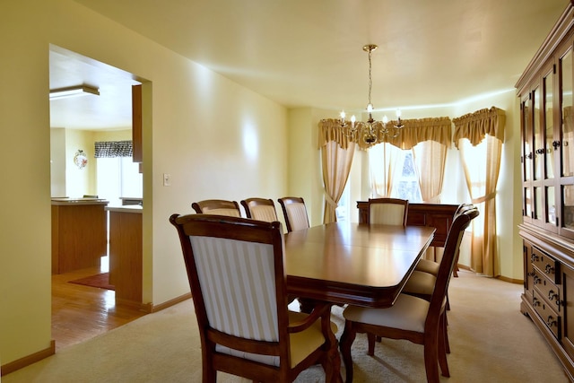 carpeted dining area with an inviting chandelier